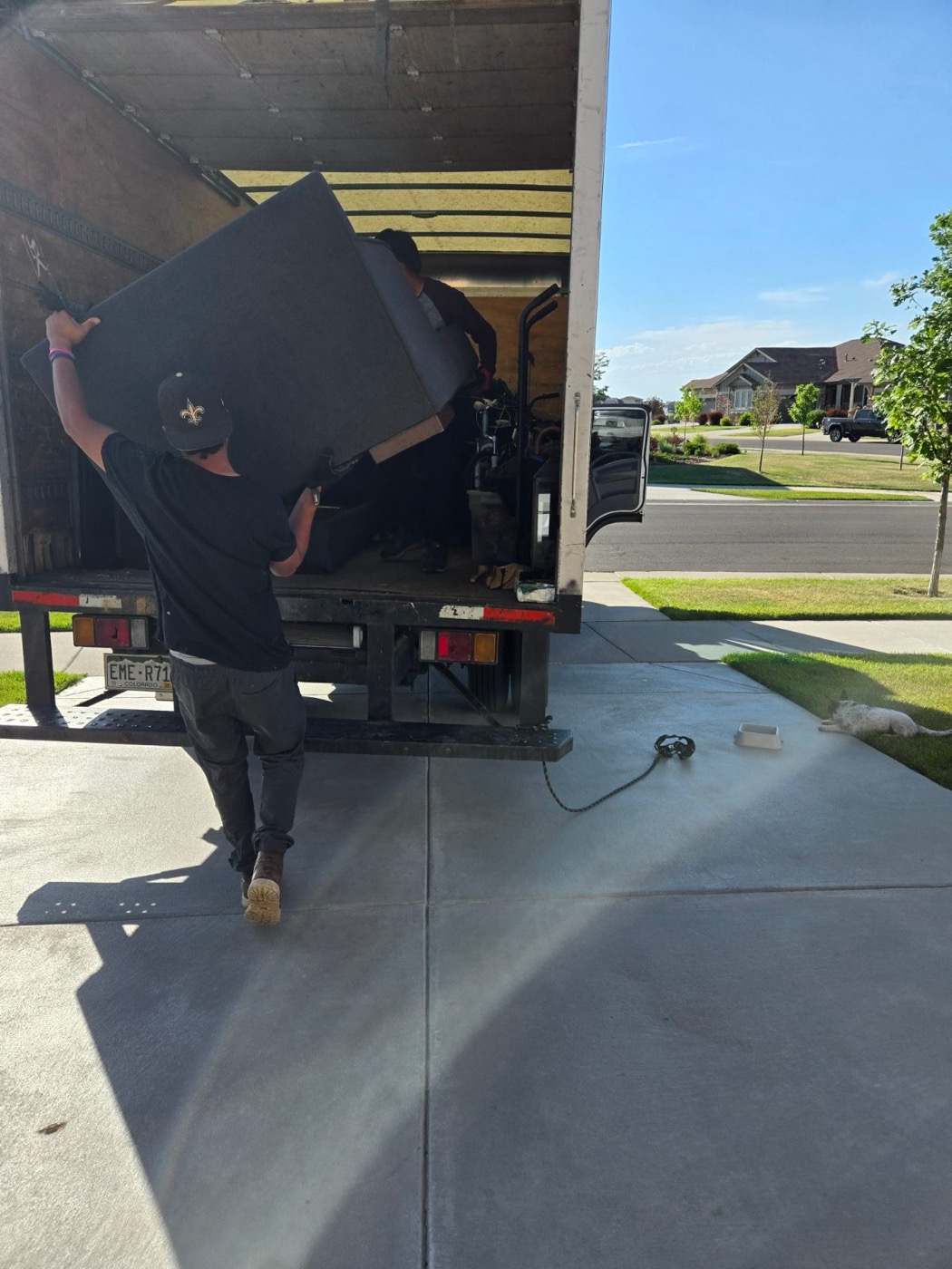 Crew member carrying a mattress into the truck from a driveway